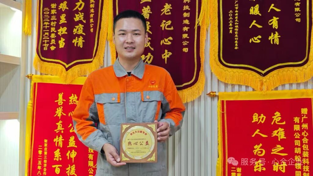 Xinhe production manager in orange uniform holding an award plaque in front of banners